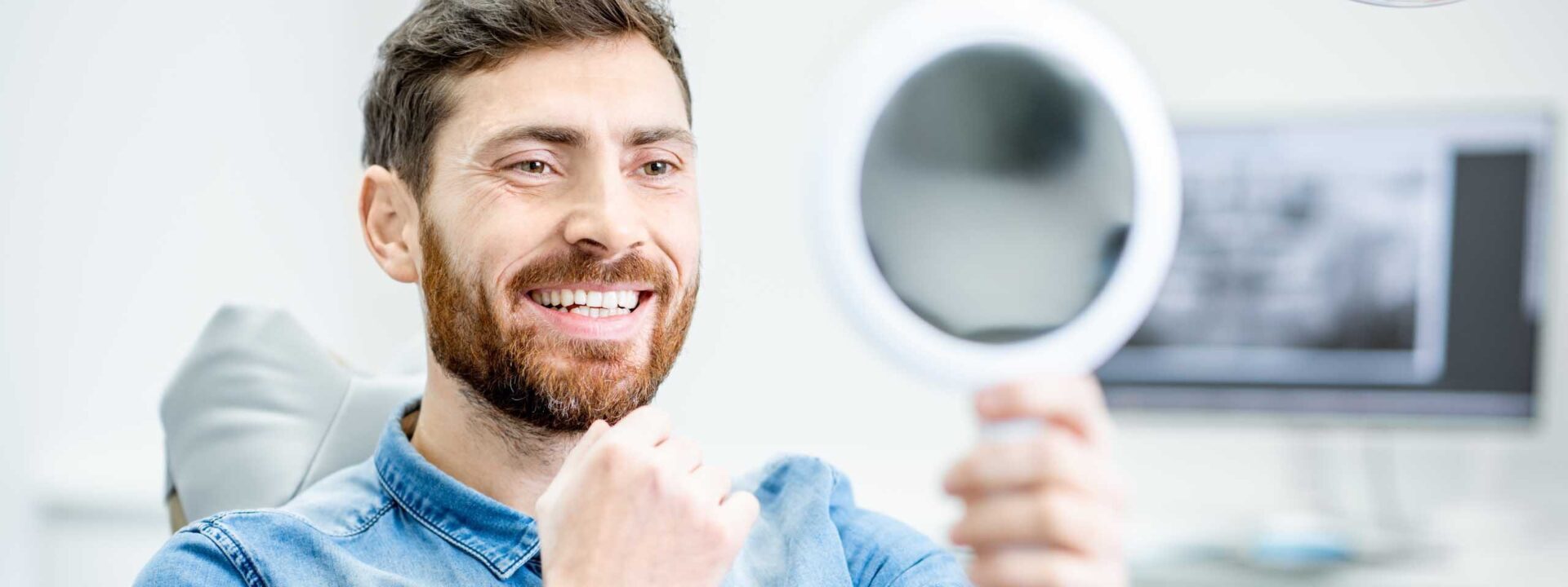 Bearded man examining his smile in the dentist's office